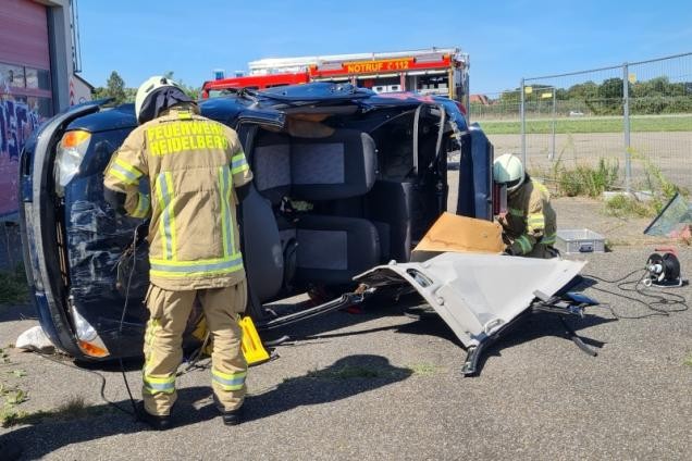 Ein Feuerwehrmann arbeitet an einem PKW der auf der Seite liegt