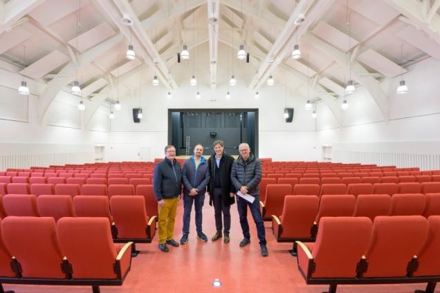 Freude bei allen Beteiligten: Das ehemalige Wilson-Theater auf dem Hospitalgelände verwandelt sich als „Rohrbacher Kulturhaus“ zu einem neuen Veranstaltungsort mit vielen Angeboten für Jung und Alt. (v.l.n.r.: Bernd Knauber, Konstantin Waldherr (beide Stadtteilverein Rohrbach e.V.), erster Bürgermeister Jürgen Odszuck und Leiter des Hochbauamtes Harald Heußer) In dem Mittelgang des Theaters stehen die Beteiligten; hinter ihnen der Raum mit Bühne