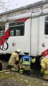 drei Feuerwehrmänner schauen unter eine alte Straßenbahn, was bei dem Unfall passiert ist