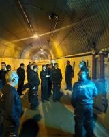 Eine Gruppe Feuerwehrangehöriger steht an einer Löschwasserentnahmestelle im Tunnel