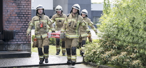 Vier Feuerwehrmänner tragen eine Leiter